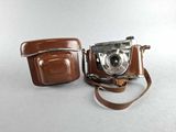 a brown camera and a brown case on a white surface