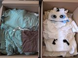 deux cartons contenant des vêtements, posés par terre