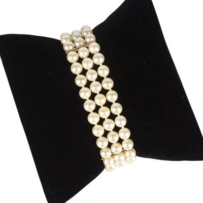 un gros plan d'un bracelet de perles blanches sur un nœud papillon en velours noir