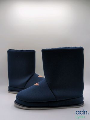 une paire de bottes bleues posées sur une surface blanche, avec une lumière en arrière-plan