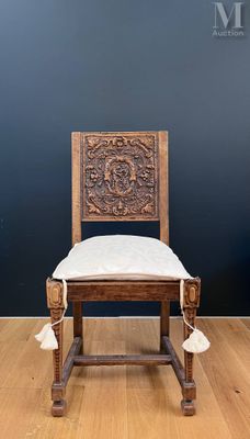 an old wooden chair with tassels on it in front of a black wall