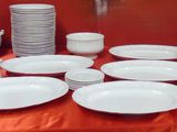 many plates and cups on a table with a red table cloth
