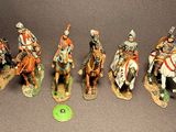 several figurines of men riding on horses with a green frisbee in front of them