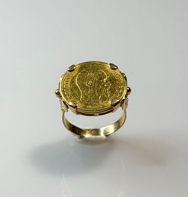 a close up of a gold ring with a coin on it