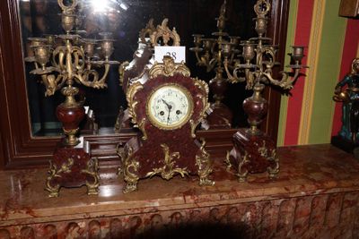 une horloge posée sur une cheminée, à côté d'un miroir