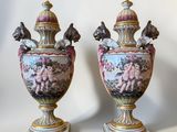 pair of antique vases with figures on them sitting on a white surface