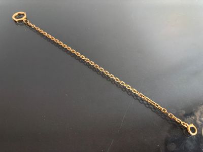 gold plated chain bracelet with a heart charm on a black surface