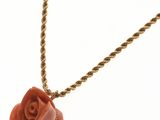 une image représentant un collier orné d'une rose, sur fond blanc
