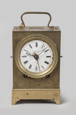 une petite horloge en laiton avec des chiffres romains sur le cadran