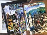 a person holding a bunch of paintings on a table