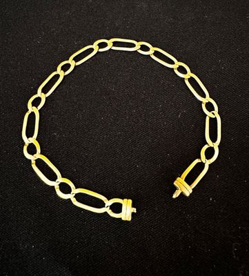 un bracelet en chaîne dorée muni d'un fermoir, sur fond noir