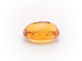 a close up of a yellow sapphire stone on a white surface