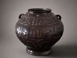 an old brown vase with writing on it sitting on a table