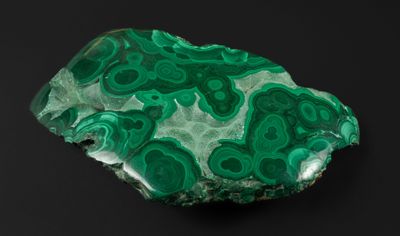 un gros plan sur un morceau de roche verte posé sur une surface noire