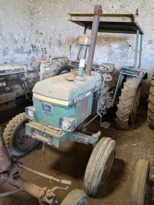 un tracteur qui est à l'abandon dans la boue, dans une grange