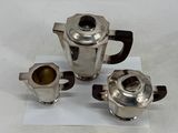 three silver teapots and a cup on a piece of paper