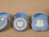 four pieces of blue and white pottery are arranged on a brown surface