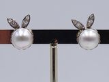 pair of pearl and diamond earrings on a black stand