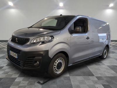 La camionnette argentée est garée dans une grande pièce au sol carrelé en damier.