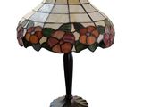 une lampe dont l'abat-jour en vitrail repose sur une table