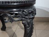 a black table with a carved top on a tile floor