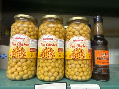 Des bocaux de pois chiches marinés et une bouteille de bière sont posés sur une étagère