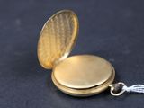 a gold pocket watch with a chain on a black surface