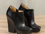 a pair of black leather ankle boots on a wooden table