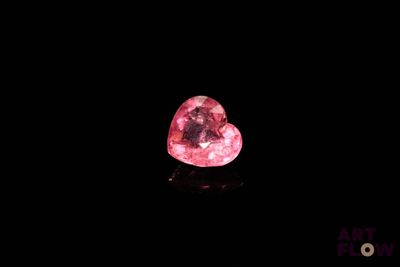 un gros plan d'un diamant rose en forme de cœur sur une surface noire