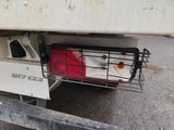 a dog in a cage attached to the back of a truck