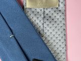 two ties and a tie bar on a pink background