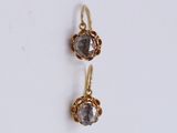 a pair of gold earrings with grey crystals on a white background