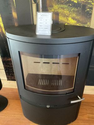 un poêle noir posé sur un plancher en bois près d'une fenêtre