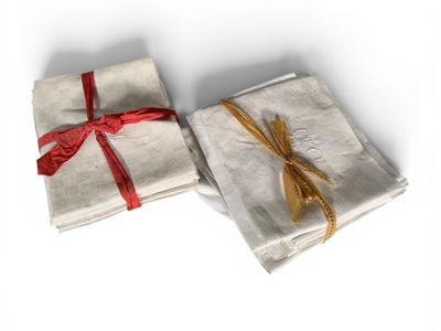 two napkins wrapped in white paper with a red ribbon