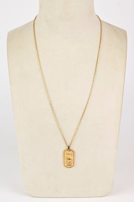 a gold necklace with a dog tag on a mannequin neck
