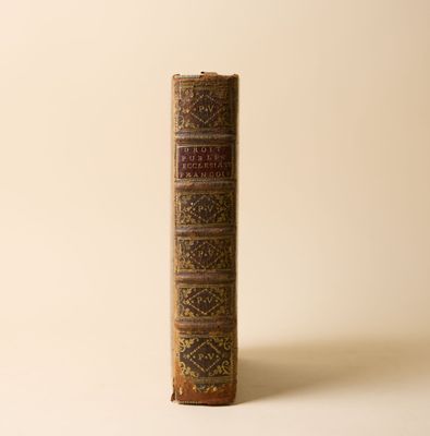 un vieux livre posé sur une table à côté d'un mur blanc