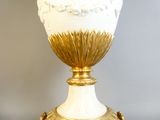 un vase blanc avec un socle doré posé sur une table