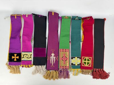 several different colored scarves hanging on a white wall