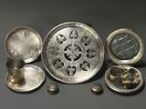 several silver objects are arranged on a table with a clock in the middle