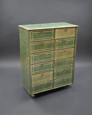 une commode verte avec des poignées en laiton sur fond gris