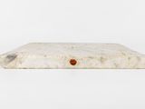 a close up of a white marble tray with a red dot on it