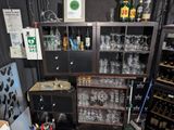 bottles and glasses on a shelf in a room with a lot of shelves