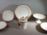 plusieurs assiettes et bols en porcelaine blanche et dorée posés sur une table