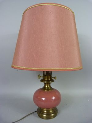 lampe en verre rose avec des finitions dorées et un abat-jour, sur fond blanc