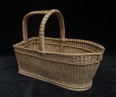 a small wicker basket with handles on a black background