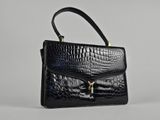un sac à main en cuir de crocodile noir sur fond blanc