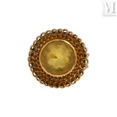 une image représentant une bague en or avec une pierre jaune au centre