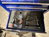 une boîte à outils bleue contenant des outils, dans un garage