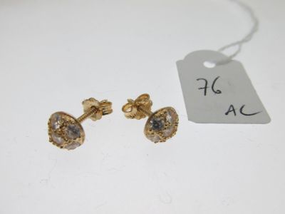 deux paires de boucles d'oreilles dorées et une étiquette posée sur une table blanche
