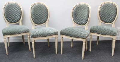 Quatre chaises sont alignées contre un mur blanc dans une pièce